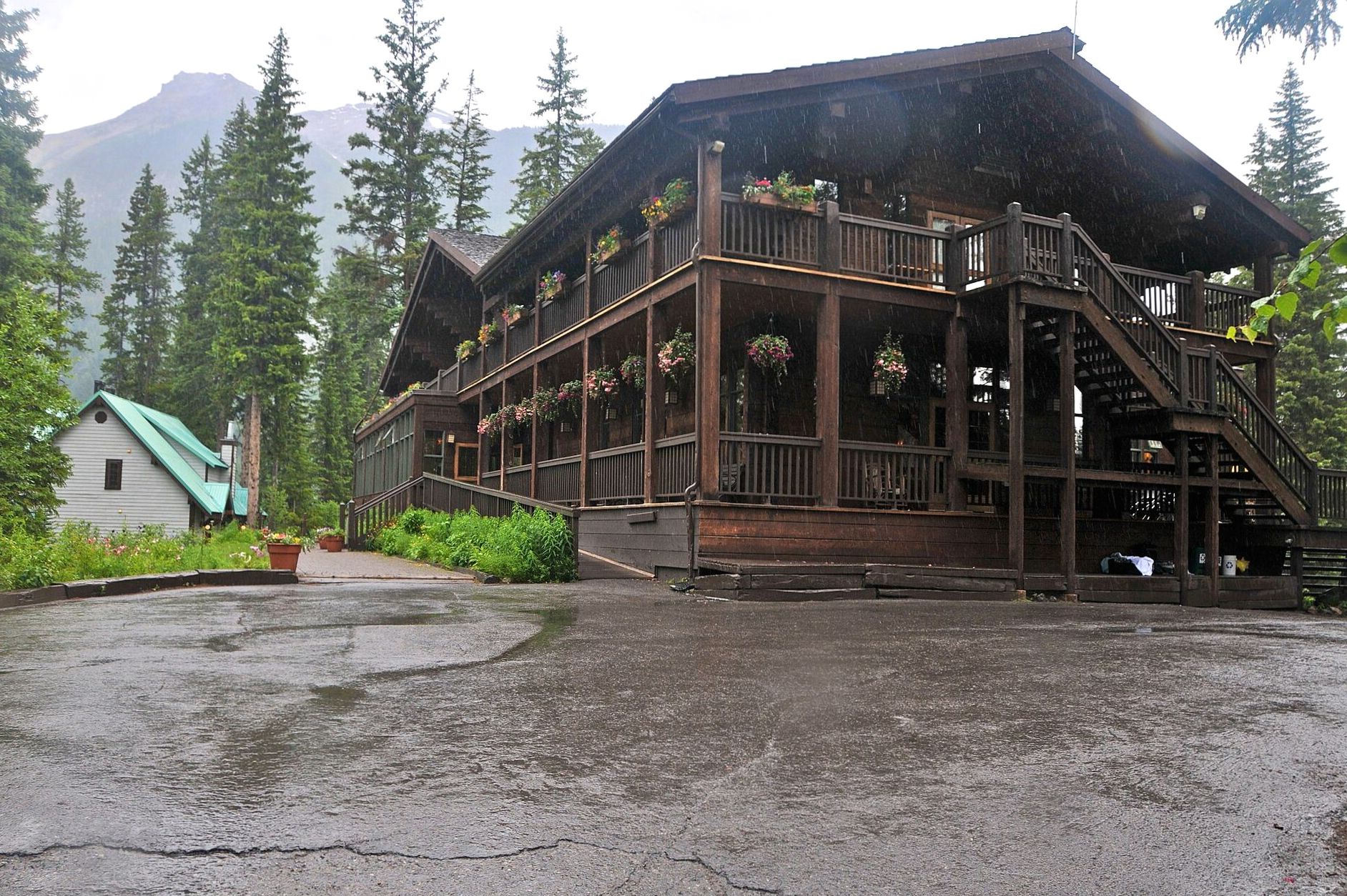 Timber lodge balconies and gabled roofline among tall conifers