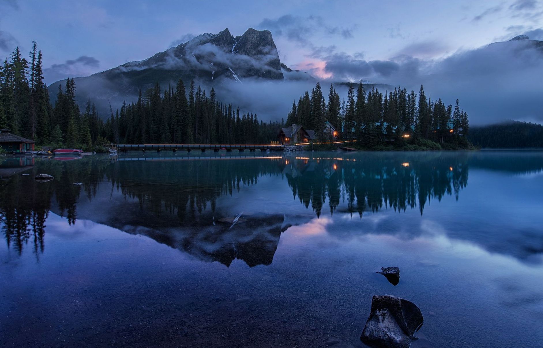 Warm light from lodge windows reflected in the lake at dusk