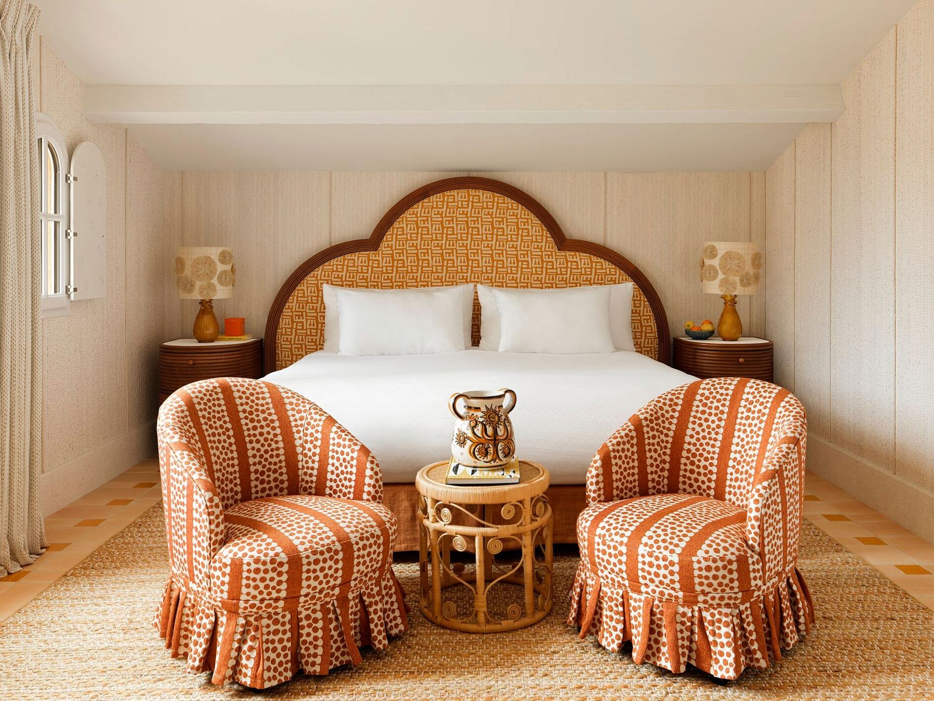 Suite interior with upholstered headboard, arched floor lamp and rattan lounge chairs