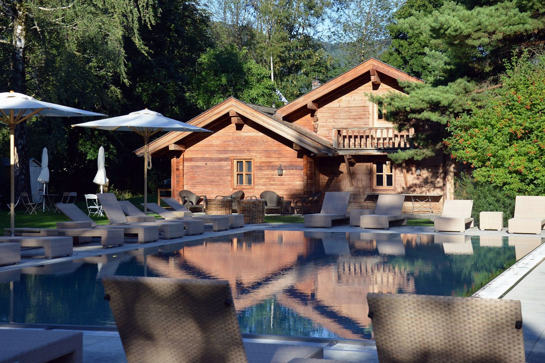 Outdoor pool terrace with loungers beside a timber resort building at dusk
